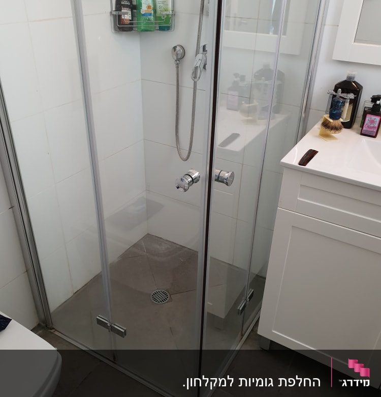 מקלחון עם בקבוקי שמפו וסבון על מדף